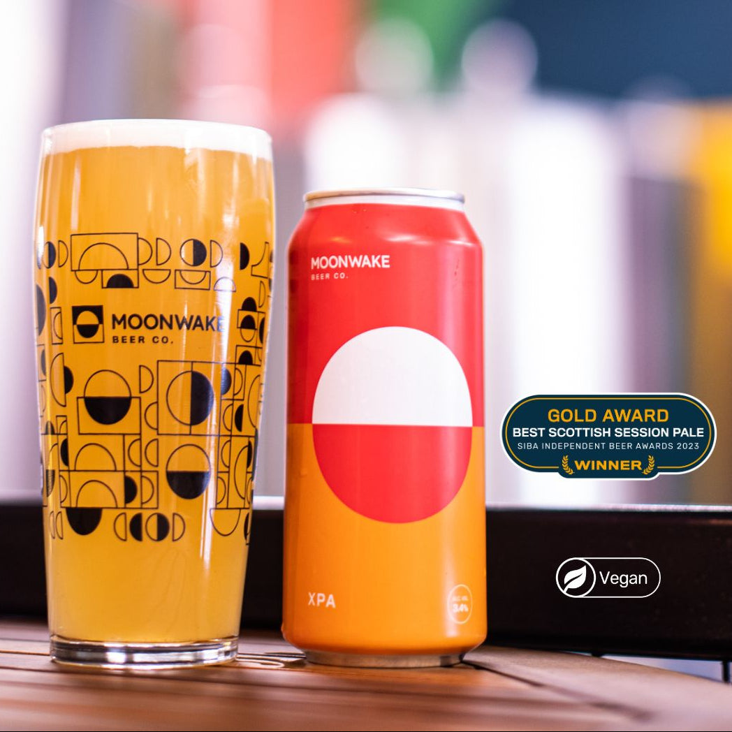 Moonwake beer can and glass on a wooden surface with a blurred background
